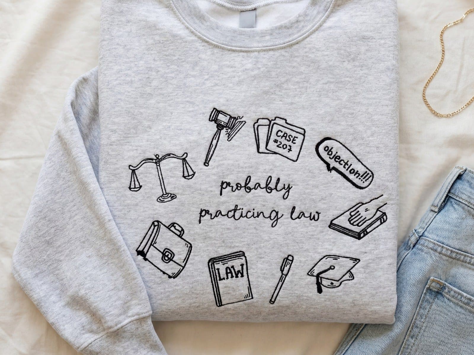 The same gray crewneck with the same law-themed stitching, folded and styled as a listing photo