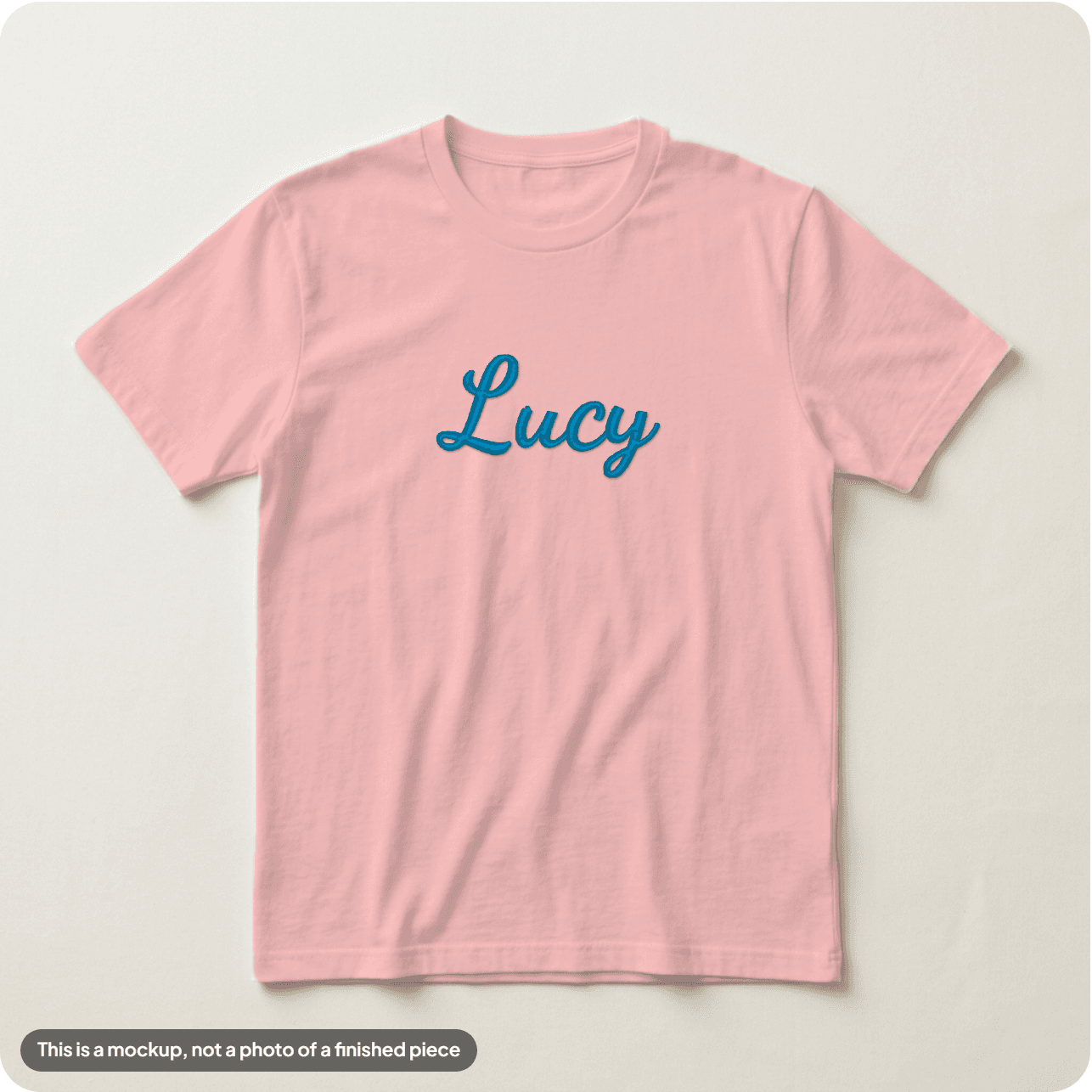 A name in a joined cursive font on a washed pink tee