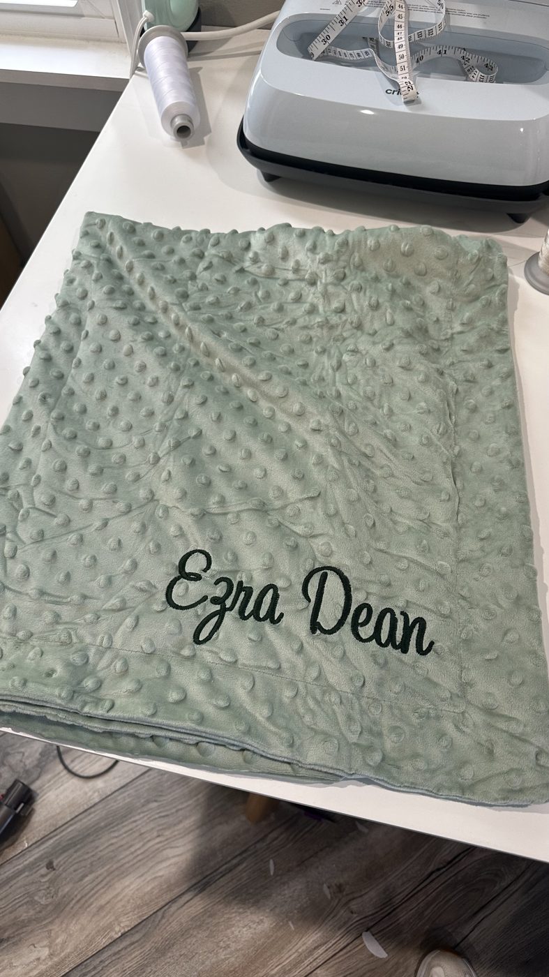A phone photo of the finished personalized baby blanket on the shop's work table