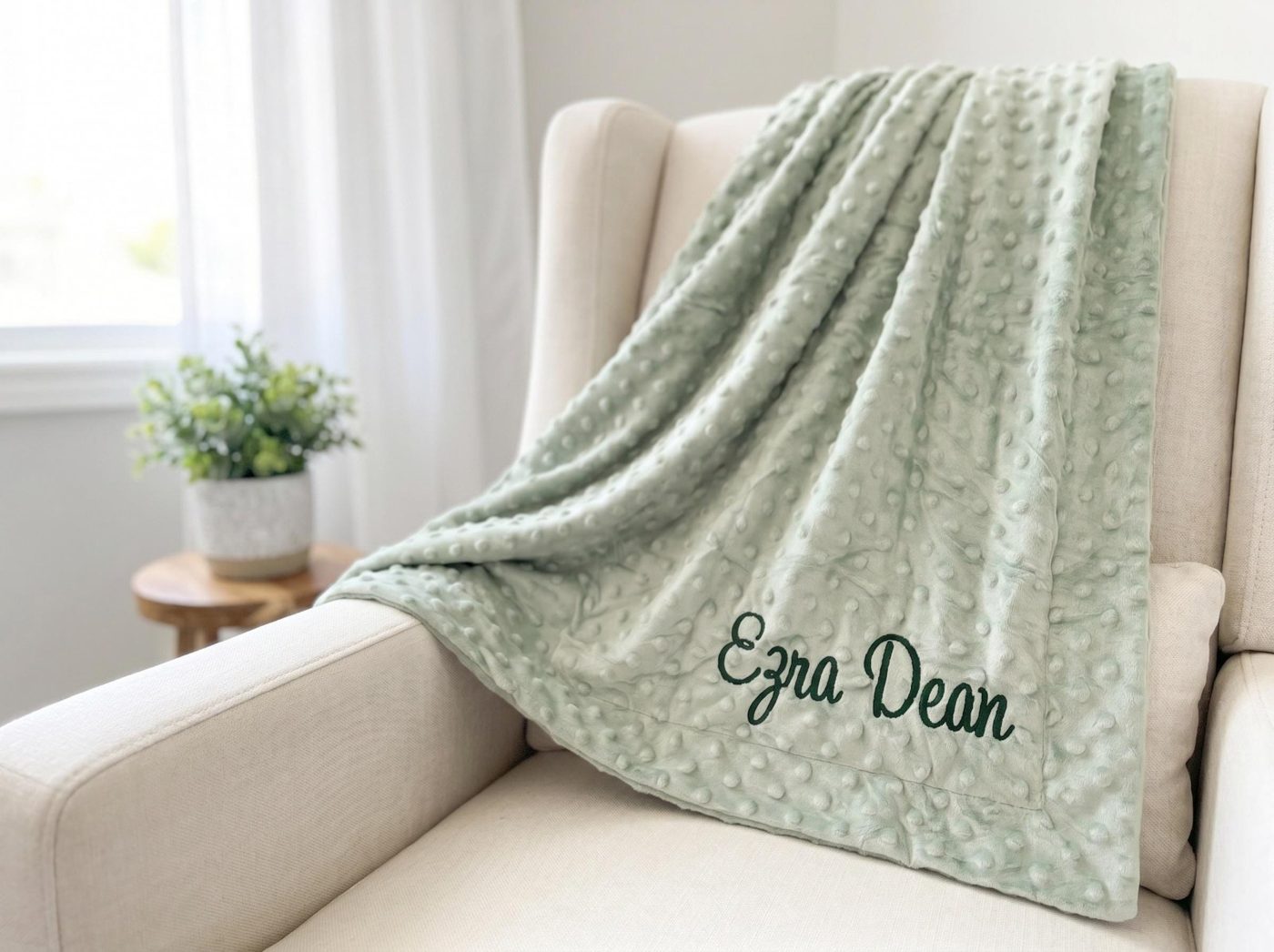 The same sage baby blanket draped over an armchair as a styled product photo