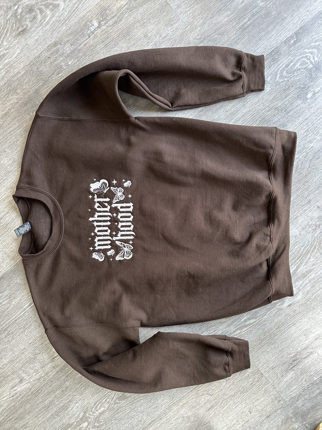 A phone photo of the finished embroidered crewneck laid out on the floor