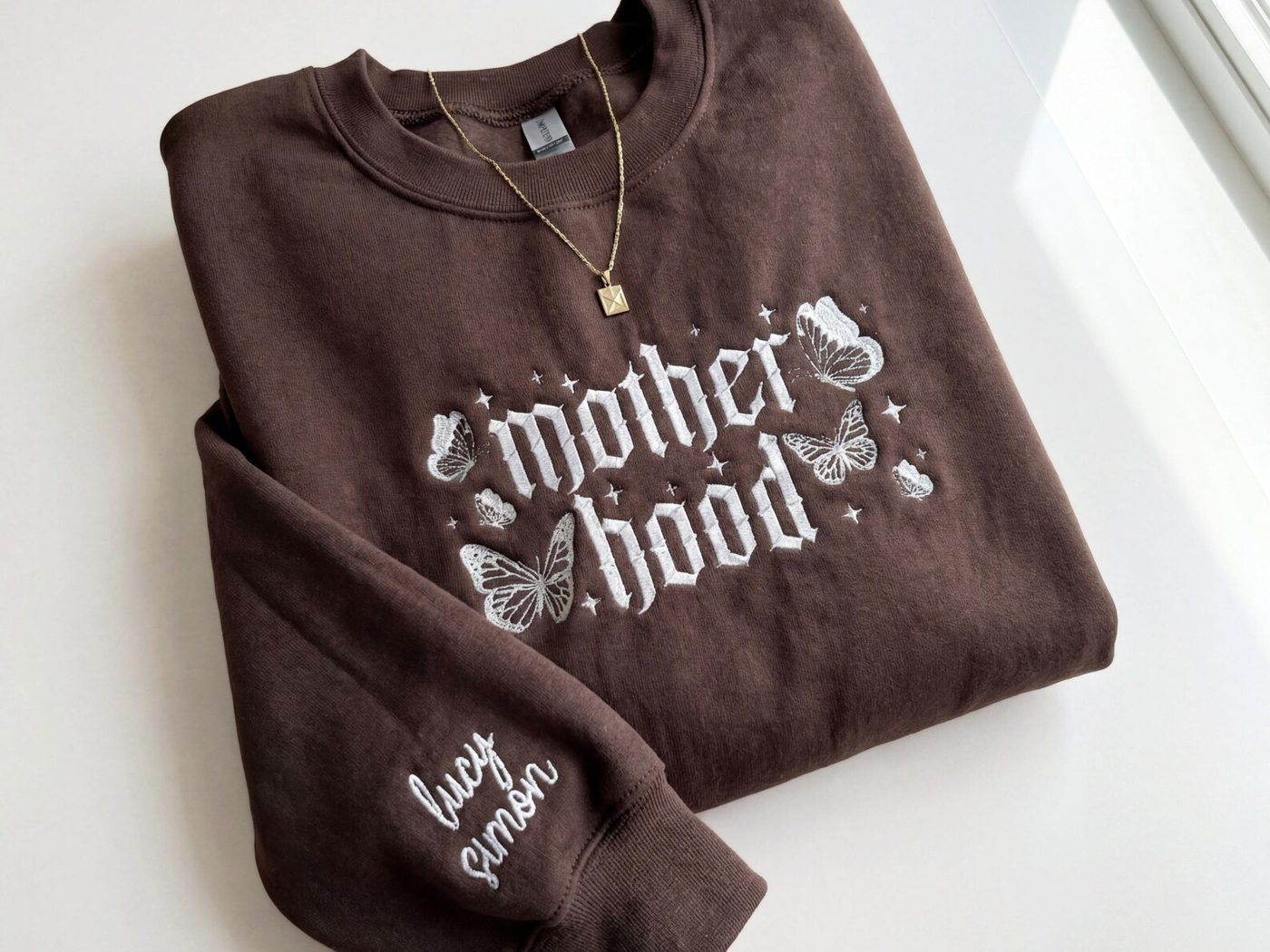 The same crewneck as a styled flat-lay product photo with a necklace